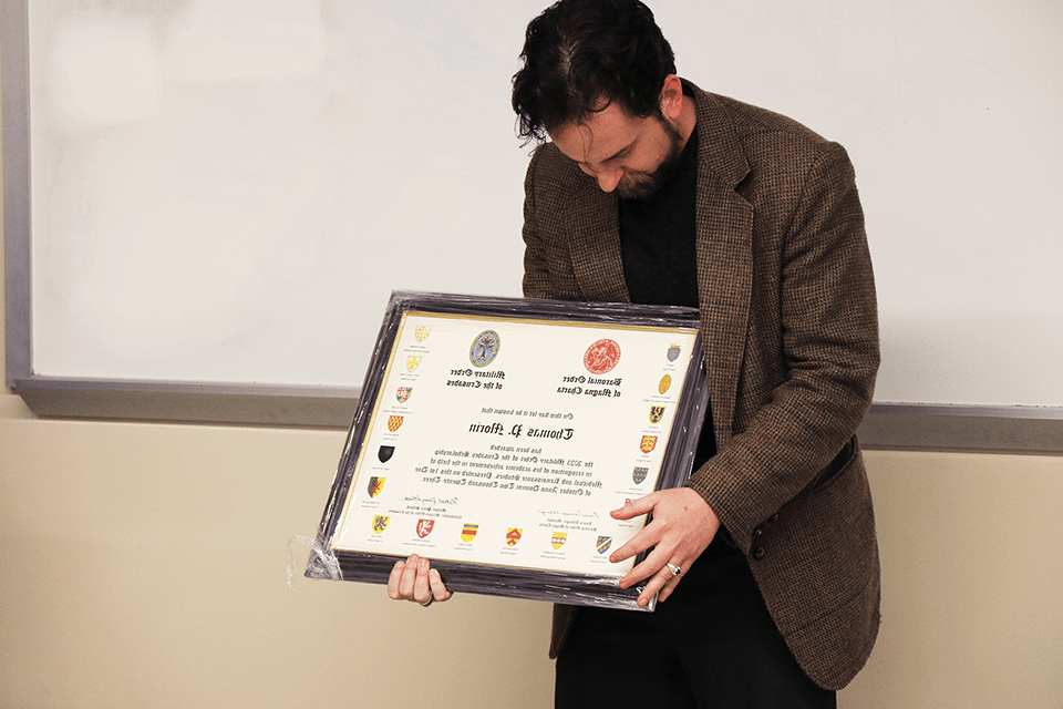 Thomas Morin admires the Military Order of the Crusades certificate honoring his scholarship.