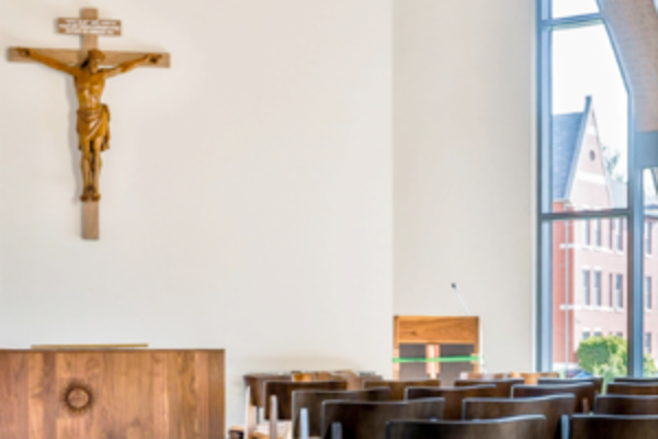 View of a chapel with seats, and altar and crucifix.